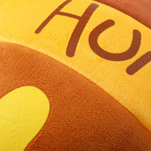 Close-up of the Brighty HoneyNest cat bed’s yellow and brown fabric, showing its fuzzy texture and decorative lettering.