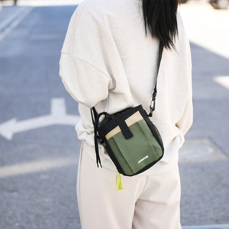 Rear crossbody view of the JUMAHE SnackPack dog treat bag, featuring adjustable carrying strap, quick-access storage and integrated waste bag dispenser for everyday walks.